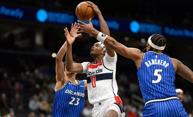 Washington Wizards guard Bilal Coulibaly (0) goes to the basket against Orlando Magic forward Paolo Banchero (5) and forward Tristan da Silva (23) during the first half of an NBA basketball game, Tuesday, Jan. 6, 2026, in Washington. (AP Photo/Nick Wass)