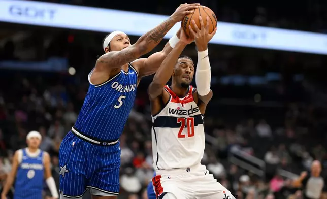 Orlando Magic forward Paolo Banchero (5) and Washington Wizards center Alex Sarr (20) battle for the ball during the first half of an NBA basketball game, Tuesday, Jan. 6, 2026, in Washington. (AP Photo/Nick Wass)