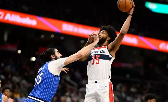 Washington Wizards forward Marvin Bagley, right, gets fouled by Orlando Magic center Goga Bitadze, left, during the first half of an NBA basketball game, Tuesday, Jan. 6, 2026, in Washington. (AP Photo/Nick Wass)