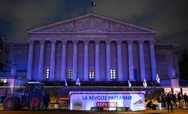 Farmers protest by the National Assembly as they protest against the Mercosur EU trade deal with South America they fear threatens their livelihoods, Tuesday, Jan. 13, 2026 in Paris. Banner reads: the peasant revolt resumes. (AP Photo/Emma Da Silva)
