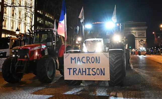 Farmers drive their tractors down the Champs-Elysees avenue as they protest over the Mercosur trade deal Tuesday, Jan. 13, 2026 in Paris. Poster reads: Macron traitor. (AP Photo/Emma Da Silva)