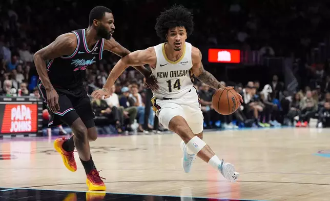 New Orleans Pelicans forward Micah Peavy (14) drives forward past Miami Heat forward Andrew Wiggins (22) during the first half of an NBA basketball game, Sunday, Jan. 4, 2026, in Miami. (AP Photo/Rebecca Blackwell)
