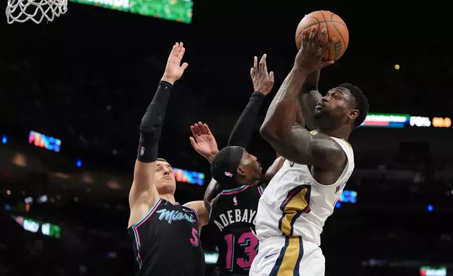 New Orleans Pelicans forward Zion Williamson shoots over Miami Heat forward Nikola Jovic (5) and center/forward Bam Adebayo (13) during the first half of an NBA basketball game, Sunday, Jan. 4, 2026, in Miami. (AP Photo/Rebecca Blackwell)