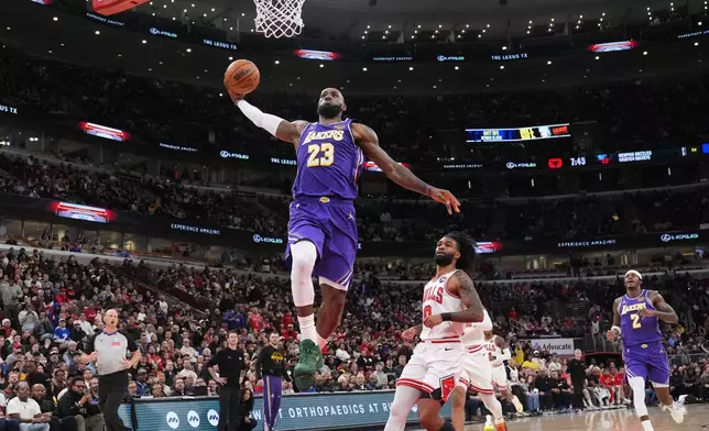 Los Angeles Lakers forward LeBron James, left, goes up for a dunk as Chicago Bulls guard Coby White looks on during the first half of an NBA basketball game in Chicago, Monday, Jan. 26, 2026. (AP Photo/Nam Y. Huh)