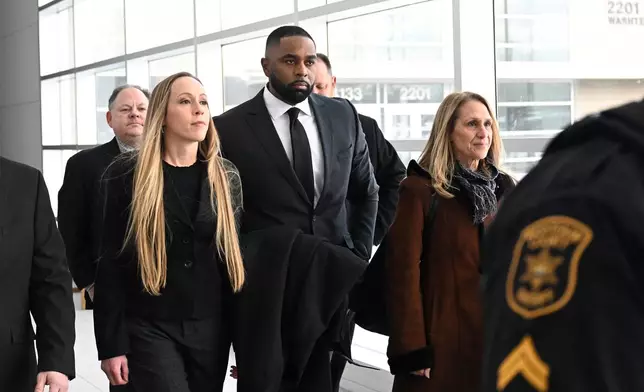 Former Michigan football coach Sherrone Moore, second from right, walks with his wife, Kelli Moore, left, and his attorney, Ellen K. Michaels, right, towards the courtroom, Thursday, Jan. 22, 2026, in Ann Arbor, Mich. (AP Photo/Jose Juarez)