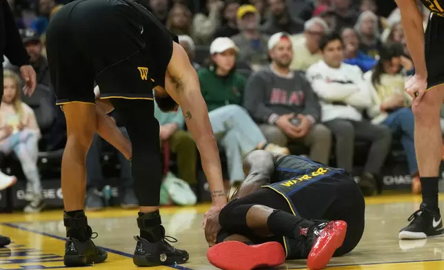 Golden State Warriors guard Stephen Curry, left, checks on forward Jimmy Butler III during the second half of an NBA basketball game against the Miami Heat in San Francisco, Monday, Jan. 19, 2026. (AP Photo/Jeff Chiu)