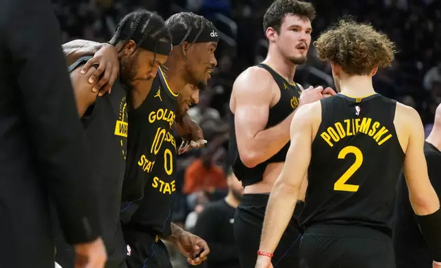 Golden State Warriors forward Jimmy Butler III, second from left, is helped off the floor by teammates during the second half of an NBA basketball game against the Miami Heat in San Francisco, Monday, Jan. 19, 2026. (AP Photo/Jeff Chiu)