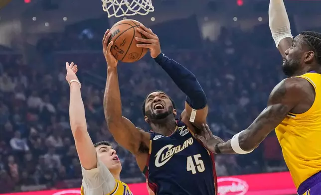 Cleveland Cavaliers guard Donovan Mitchell (45) shoots between Los Angeles Lakers forward Jake LaRavia, left, and center Deandre Ayton, right, in the first half of an NBA basketball game in Cleveland, Wednesday, Jan. 28, 2026. (AP Photo/Sue Ogrocki)