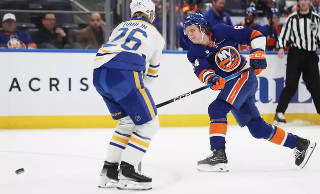 New York Islanders center Calum Ritchie (64) passes the puck around Buffalo Sabres defenseman Rasmus Dahlin (26) during the second period of an NHL hockey game, Saturday, Jan. 24, 2026, in Elmont, N.Y. (AP Photo/Heather Khalifa)