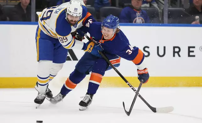 Buffalo Sabres right wing Alex Tuch (89) and New York Islanders defenseman Adam Boqvist (34) go after the puck during the third period of an NHL hockey game, Saturday, Jan. 24, 2026, in Elmont, N.Y. (AP Photo/Heather Khalifa)