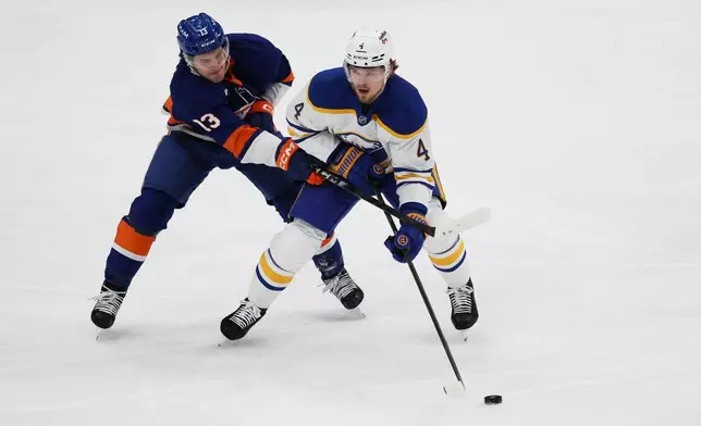 New York Islanders center Mathew Barzal (13) and Buffalo Sabres defenseman Bowen Byram (4) go after the puck during the first period of an NHL hockey game, Saturday, Jan. 24, 2026, in Elmont, N.Y. (AP Photo/Heather Khalifa)
