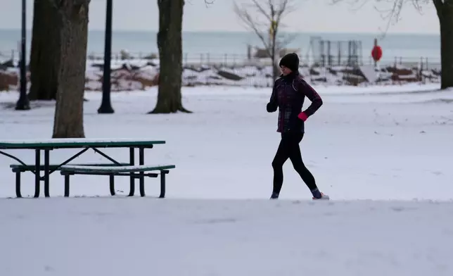 A person jogs on a snow-covered sidewalk during a cold weather day in Evanston, Ill., Thursday, Jan. 22, 2026. (AP Photo/Nam Y. Huh)
