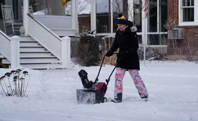 A person cleans snow during a cold weather day in Evanston, Ill., Thursday, Jan. 22, 2026. (AP Photo/Nam Y. Huh)