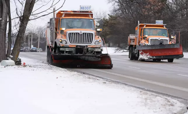 Snow plows drive through a street during cold weather in Northbrook, Ill., Thursday, Jan. 22, 2026. (AP Photo/Nam Y. Huh)