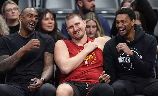 Returning from an injury, Denver Nuggets center Nikola Jokić, center, jokes with player development coaches Darrell Arthur, left, and Cam Griffin, right, before warming up for an NBA basketball game against the Los Angeles Clippers, Friday, Jan. 30, 2026, in Denver. (AP Photo/David Zalubowski)