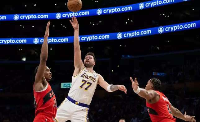 Los Angeles Lakers guard Luka Doncic (77) shoots over Toronto Raptors guard Ochai Agbaji (30) during the first half of an NBA basketball game in Los Angeles, Sunday, Jan. 18, 2026. (AP Photo/Kyusung Gong)