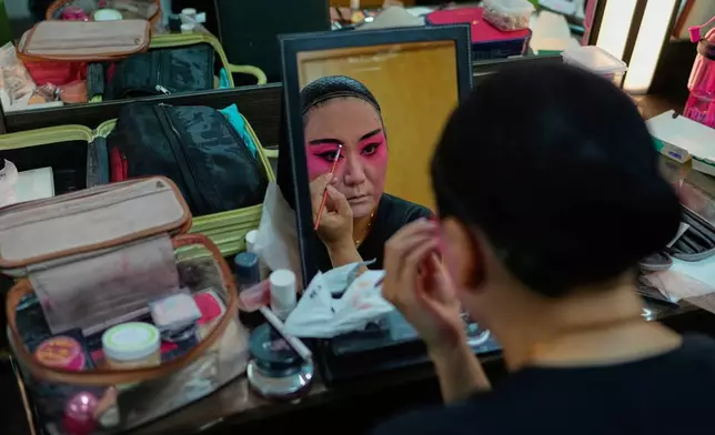 A Peking Opera actress applies makeup backstage before a show in Beijing, China, Sunday, Sept. 7, 2025. (AP Photo/Mahesh Kumar A.)