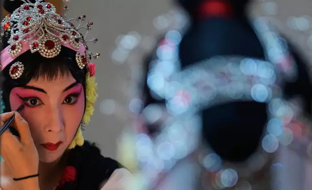 A Peking Opera actress applies makeup backstage before a show in Beijing, China, Sunday, Sept. 7, 2025. (AP Photo/Mahesh Kumar A.)