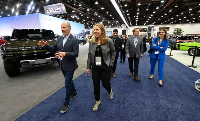 FILE - Todd Szott, left, president of the Detroit Auto Dealers Association and dealer partner at Szott Auto Group, talks with Rep. Hillary Scholten, D-Mich., center left, as Sen. Gary Peters, D-Mich., second from right, talks with his press secretary, Brennan Sullivan, as they tour the Detroit Auto Show, Friday, Jan. 10, 2025, in Detroit. (AP Photo/Jose Juarez. file)