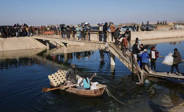 Displaced Syrians walk to cross at a river crossing near the village of Rasm al-Harmil al-Imam in the eastern Aleppo countryside, near the front line with the Kurdish-led Syrian Democratic Forces, in Deir Hafer, Syria, Friday, Jan. 16, 2026. (AP Photo/Ghaith Alsayed)