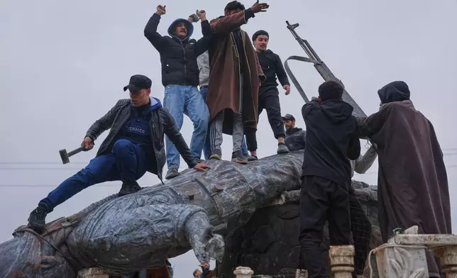 Residents topple a statue of a female Kurdish fighter after the takeover of the town by Syrian government forces from U.S.-backed Syrian Democratic Forces (SDF), in Tabqa, eastern Syria, Sunday, Jan. 18, 2026. (AP Photo/Ghaith Alsayed)
