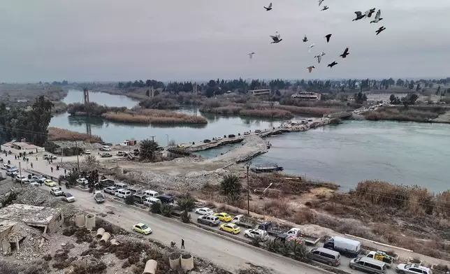 People cross a bridge over the Euphrates River in Deir Ezzor, eastern Syria, after Syrian government forces took control of the area following the withdrawal of Kurdish-led Syrian Democratic Forces (SDF), Thursday, Jan. 22, 2026. (AP Photo/Ghaith Alsayed)