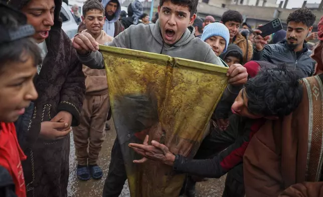 Local youth tear up an SDF flag as they celebrate after Syrian government troops took control of the town from U.S.-backed Syrian Democratic Forces (SDF) during an ongoing push against Kurdish-led forces, in Tabqa, eastern Syria, Sunday, Jan. 18, 2026. (AP Photo/Omar Albam)