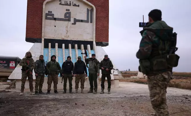 Syrian government soldiers pose for a photo taken by another soldier at the entrance to Raqqa, Syria, Saturday, Jan. 17, 2026. (AP Photo/Ghaith Alsayed)