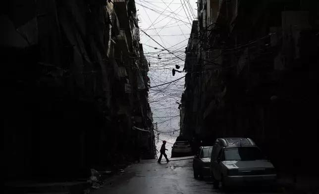 FILE - A man crosses a street in the predominantly Kurdish Sheikh Maqsoud neighborhood after days of fighting between government forces and Kurdish fighters in the northern city of Aleppo, Syria, Tuesday, Jan. 13, 2026. (AP Photo/Ghaith Alsayed)