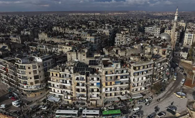FILE - An aerial view shows buses carrying displaced residents as they return to the Sheikh Maqsoud neighborhood after days of fighting between government forces and Kurdish fighters in the northern city of Aleppo, Syria, Tuesday, Jan. 13, 2026. (AP Photo/Omar Albam)