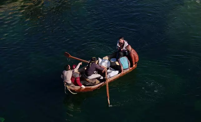 FILE - Displaced Syrians cross a river in a boat near the village of Rasm al-Harmil al-Imam in the eastern Aleppo countryside, near the front line with the Kurdish-led Syrian Democratic Forces, in Deir Hafer, Syria, Friday, Jan. 16, 2026. (AP Photo/Ghaith Alsayed)