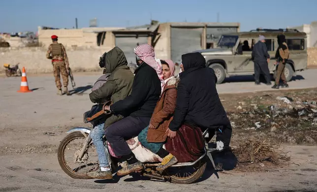 FILE - A displaced Syrian family ride on a motorcycle near the humanitarian crossing declared by the Syrian army in the village of Hamima, in the eastern Aleppo countryside, near the front line with the Kurdish-led Syrian Democratic Forces, in Deir Hafer, Syria, Thursday, Jan. 15, 2026. (AP Photo/Ghaith Alsayed)