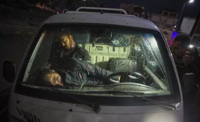 EDS NOTE: GRAPHIC CONTENT - The bodies of two civilians lie inside a car after fighting during the takeover of the city by Syrian government troops from the Kurdish-led, U.S.-backed Syrian Democratic Forces (SDF), in Raqqa, northeastern Syria, Sunday, Jan. 18, 2026. (AP Photo/Omar Albam)