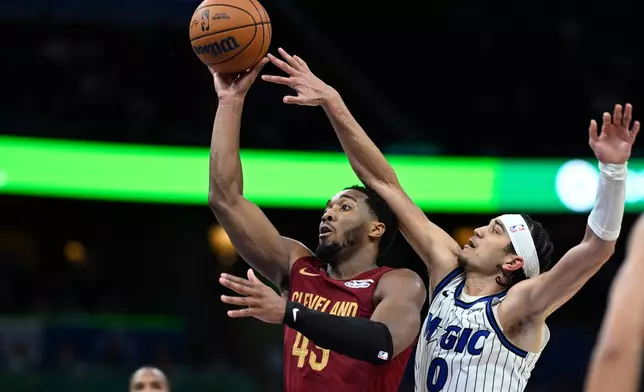 Cleveland Cavaliers guard Donovan Mitchell, second from right, goes up to shoot as Orlando Magic guard Anthony Black (0) defends during the second half of an NBA basketball game, Saturday, Jan. 24, 2026, in Orlando, Fla. (AP Photo/Phelan M. Ebenhack)