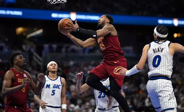Cleveland Cavaliers guard Donovan Mitchell (45) goes up to shoot between Orlando Magic forward Tristan da Silva (23) and guard Anthony Black (0) during the second half of an NBA basketball game, Saturday, Jan. 24, 2026, in Orlando, Fla. (AP Photo/Phelan M. Ebenhack)