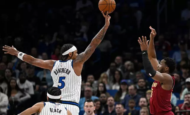 Orlando Magic forward Paolo Banchero (5) blocks a shot by Cleveland Cavaliers guard Donovan Mitchell, right, during the first half of an NBA basketball game, Saturday, Jan. 24, 2026, in Orlando, Fla. (AP Photo/Phelan M. Ebenhack)