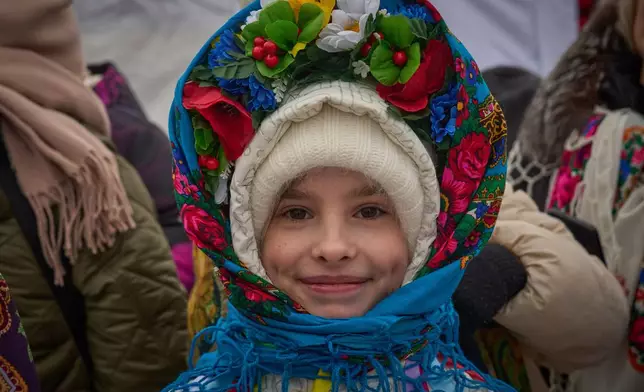 A girl watches people plunging into icy water during celebrations of Epiphany in Kyiv, Ukraine, Tuesday, Jan. 6, 2026. (AP Photo/Efrem Lukatsky)