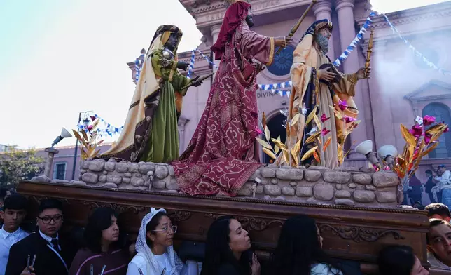 Catholics carry a religious float transporting statues representing the Three Wise Men: Balthazar, Gaspar and Melchior, during a procession marking Three Kings Days, also known as feast day of The Epiphany, at the Guardia Viejo neighborhood in Guatemala City, Tuesday, Jan. 6, 2026. (AP Photo/Moises Castillo)