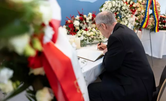 Swiss President Guy Parmelin writes in a condolence book prior to the official commemorative ceremony for the victims of the deadly fire at the "Le Constellation" bar in Crans-Montana at the CERM in Martigny, Switzerland, Friday, Jan. 9, 2026. (Michael Buholzer/Keystone/Pool via AP)