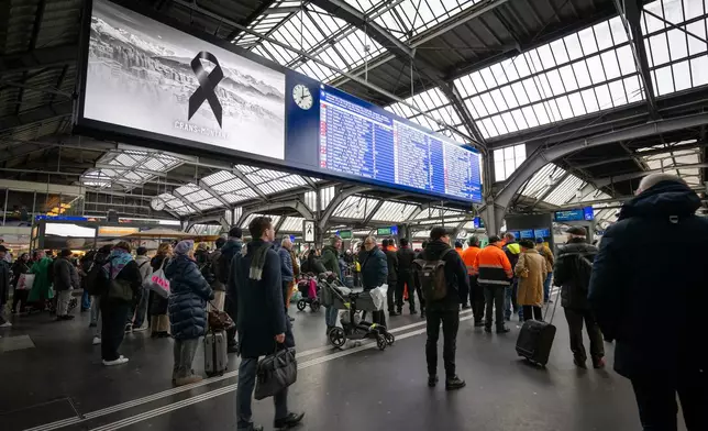 People observe a minute of silence on the national day of mourning, at the main station in Zurich, Switzerland, Friday Jan. 9, 2026, following the deadly fire at the "Le Constellation" bar in Crans-Montana. (Andreas Becker/Keystone via AP)