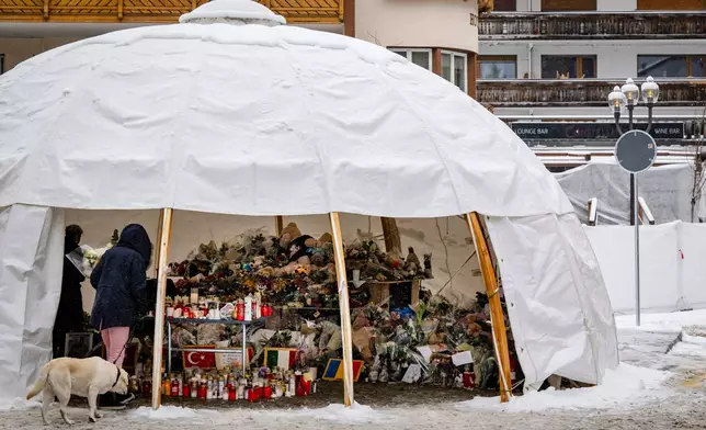 Mourners gather around flowers and candles to commemorate the victims of the "Le Constellation" bar and lounge's fire, in Crans-Montana, Switzerland, Thursday, Jan. 8, 2026. (Jean-Christophe Bott/Keystone via AP)