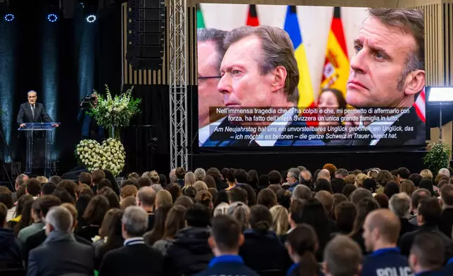 Swiss Federal President Guy Parmelin, left, delivers his statement as Former Grand Duke of Luxembourg Henri, left, and Emmanuel Macron, right, President of France appear on the screen, during the official commemorative ceremony for the victims of the deadly fire at the "Le Constellation" bar in Crans-Montana, in Martigny, Switzerland, Friday, Jan. 9, 2026. (Laurent Gillieron/Keystone/Pool via AP)