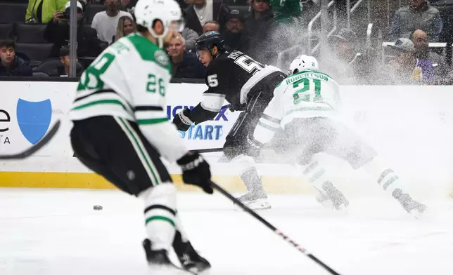 Los Angeles Kings right wing Quinton Byfield, center, battles for the puck against Dallas Stars left wing Jason Robertson (21) as Stars defenseman Alexander Petrovic (28) skates during the second period of an NHL hockey game, Monday, Jan. 12, 2026, in Los Angeles. (AP Photo/Jessie Alcheh)