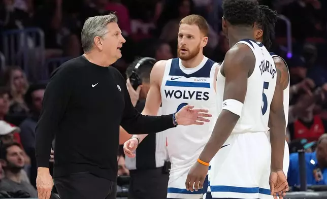 Minnesota Timberwolves head coach Chris Finch, left, talks with guards Donte Divincenzo, center, Anthony Edwards (5), and Bones Hyland, obscured, during the first half of an NBA basketball game against the Miami Heat, Saturday, Jan. 3, 2026, in Miami. (AP Photo/Rebecca Blackwell)