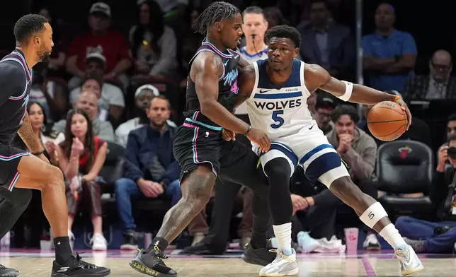Minnesota Timberwolves guard Anthony Edwards (5) looks for an opening past Miami Heat guard Davion Mitchell (45) during the first half of an NBA basketball game, Saturday, Jan. 3, 2026, in Miami. (AP Photo/Rebecca Blackwell)