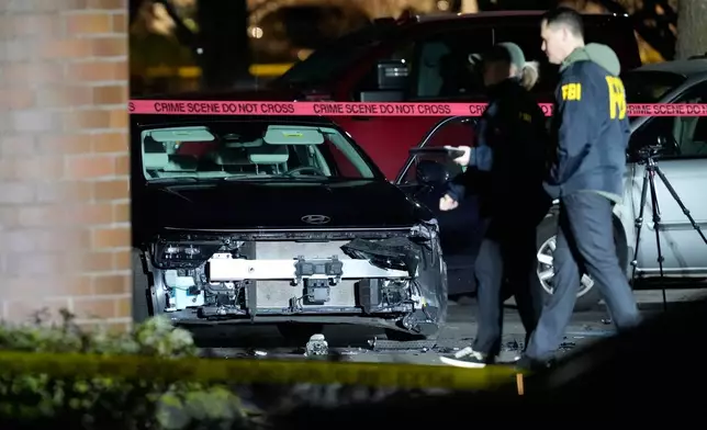 A damaged car is seen as law enforcement officials work the scene following reports that federal immigration officers shot and wounded people in Portland, Ore., Thursday, Jan. 8, 2026. (AP Photo/Jenny Kane)