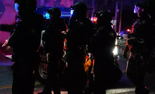 Portland police officers walk outside the U.S. Immigration and Customs Enforcement facility during a protest on Thursday, Jan. 8, 2026, in Portland, Ore. (AP Photo/Jenny Kane)