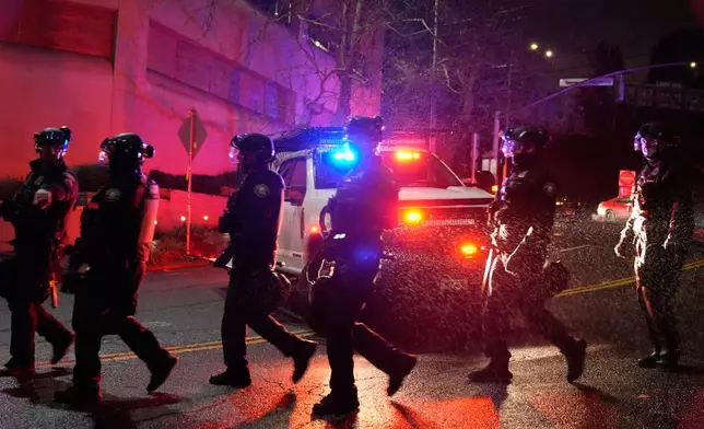 Portland police officers walk outside the U.S. Immigration and Customs Enforcement facility on Thursday, Jan. 8, 2026, in Portland, Ore. (AP Photo/Jenny Kane)