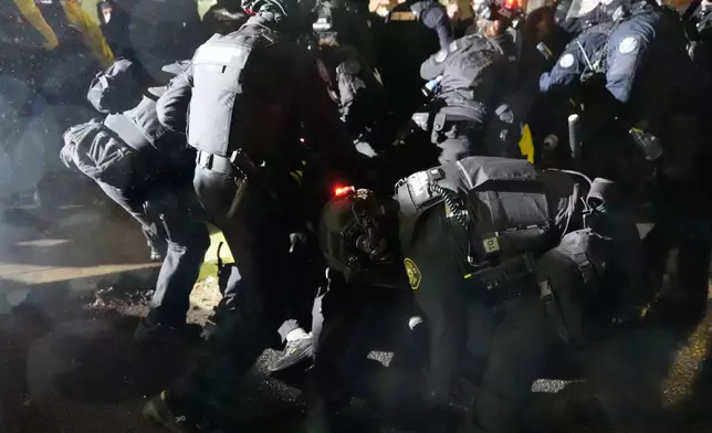 Law enforcement move to detain a protester outside the U.S. Immigration and Customs Enforcement facility on Thursday, Jan. 8, 2026, in Portland, Ore. (AP Photo/Jenny Kane)