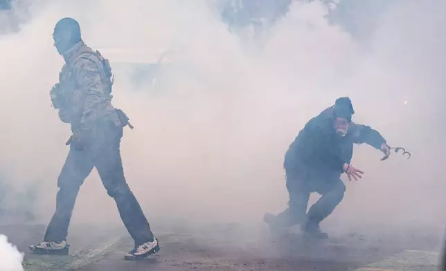 A man arrested by federal agents moments prior escapes in handcuffs after tear gas went off, Wednesday, Jan. 21, 2026, in Minneapolis. (AP Photo/Angelina Katsanis)